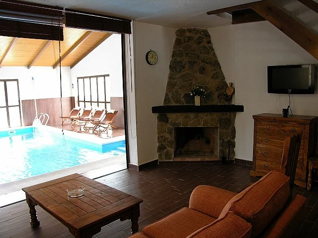 Salón con chimenea y vistas a la piscina de Casa Rural La Serijuelas