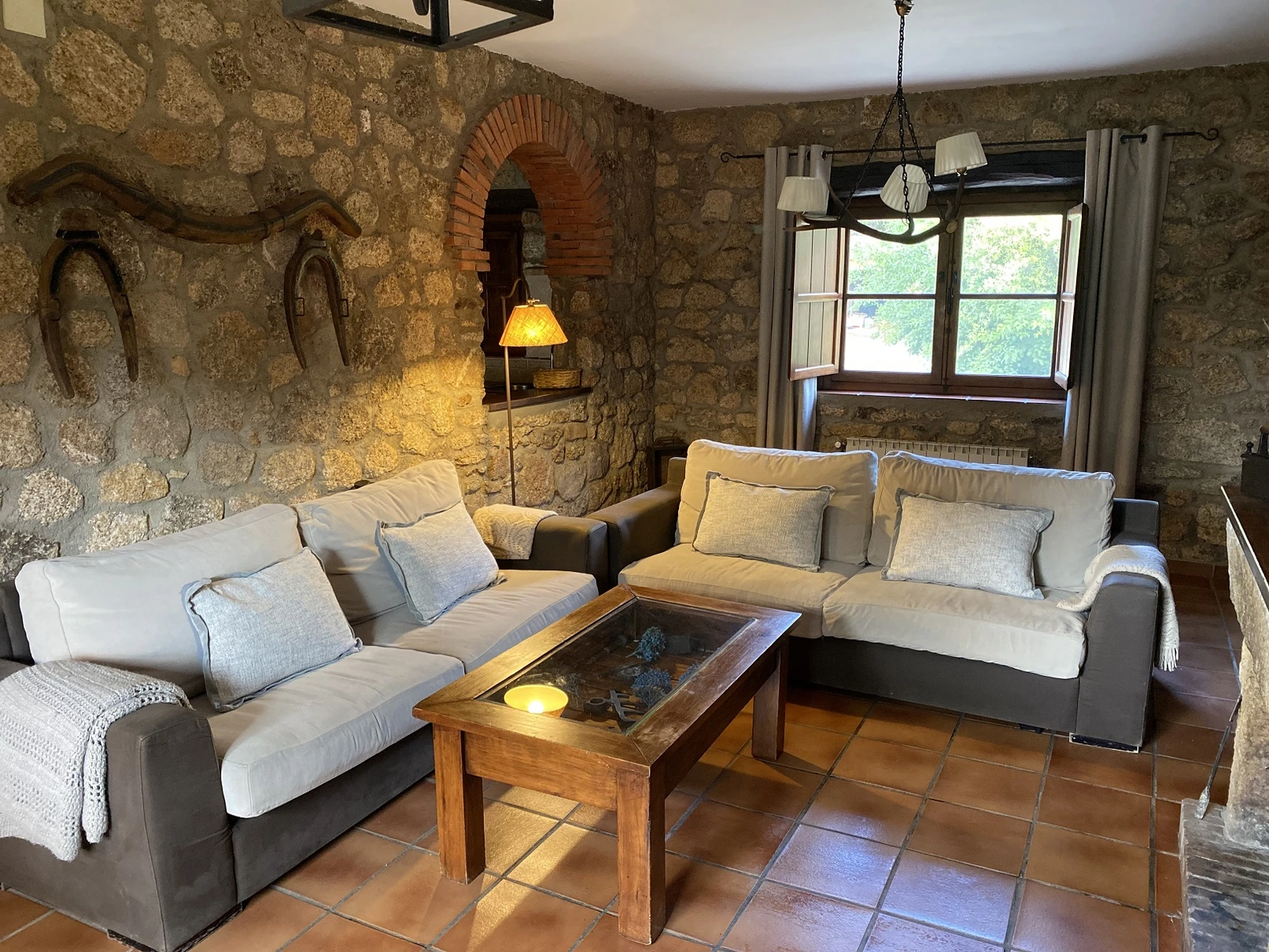 Salón con sofás, paredes de piedra y decoración rural · Casa Rural Virgen de la Cabeza