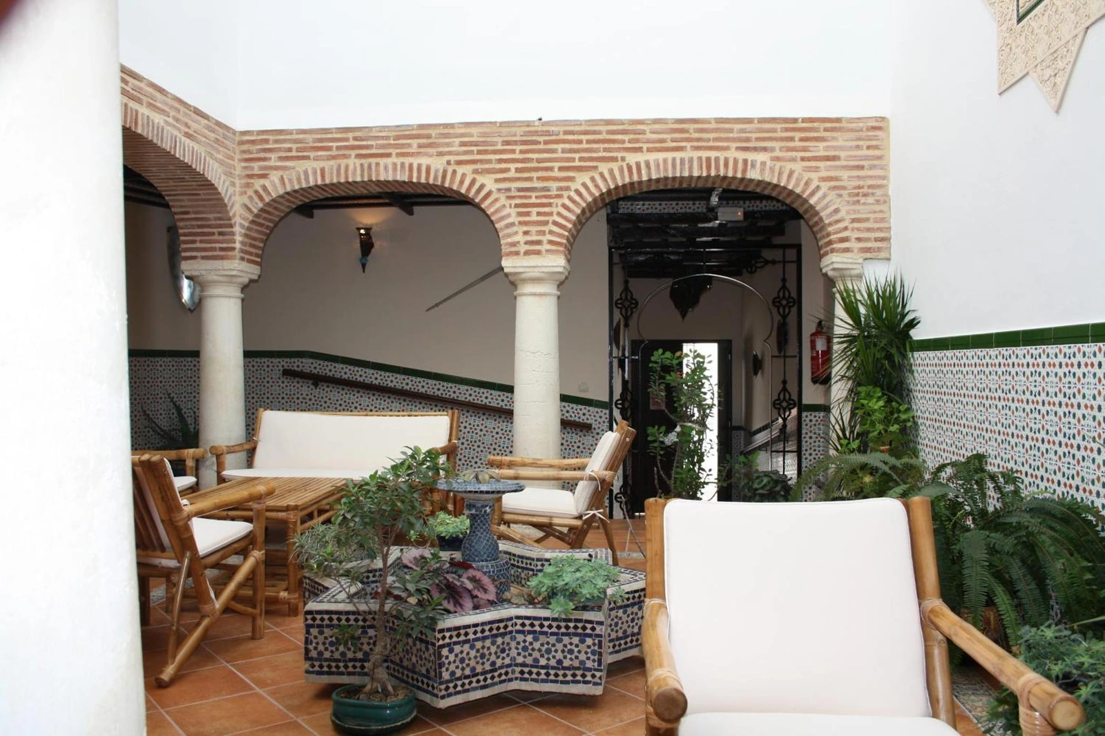 Patio de Casa Rural Sidonia, con arcos de ladrillo y fuente de azulejos · Casa Rural Sidonia