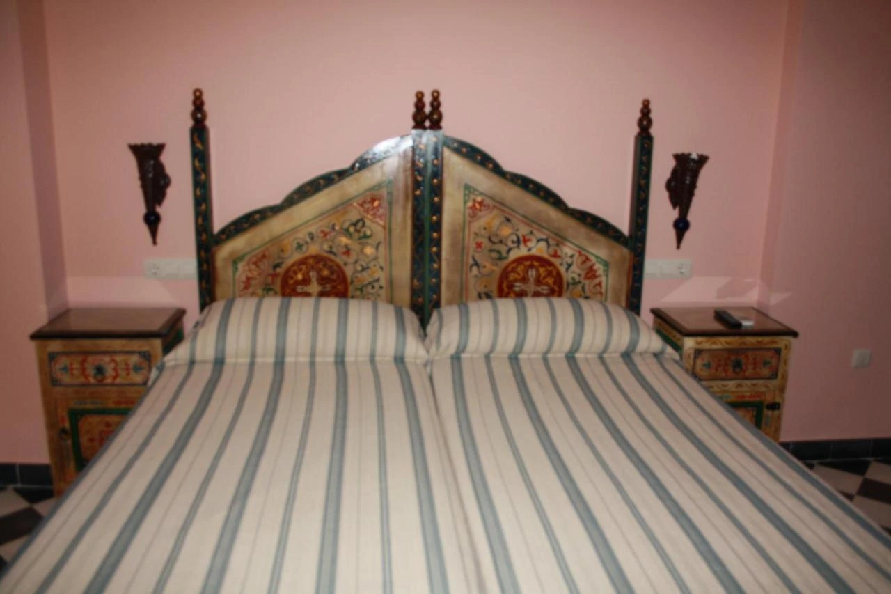 Dormitorio de Casa Rural Sidonia con cabecero pintado y paredes rosadas · Casa Rural Sidonia