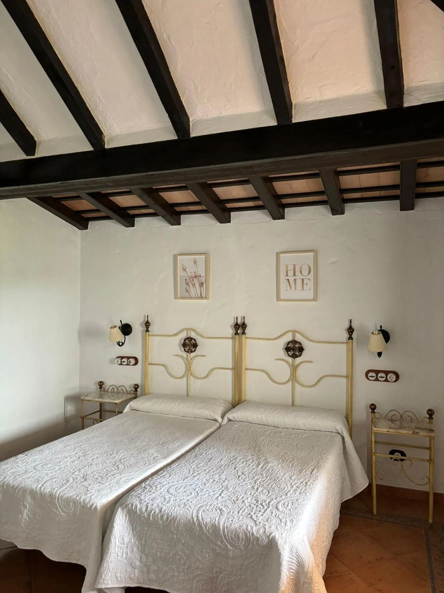 Dormitorio del hotel Cortijo Huerta Dorotea con techo de vigas · Cortijo Huerta Dorotea