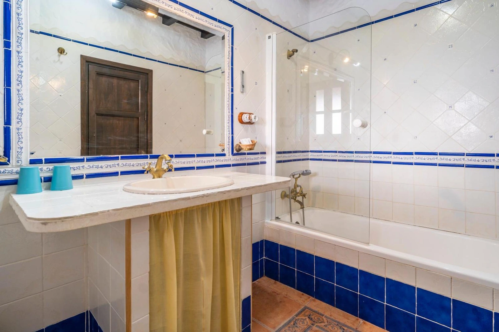 Baño del hotel Cortijo Huerta Dorotea con bañera y azulejos blancos y azules · Cortijo Huerta Dorotea