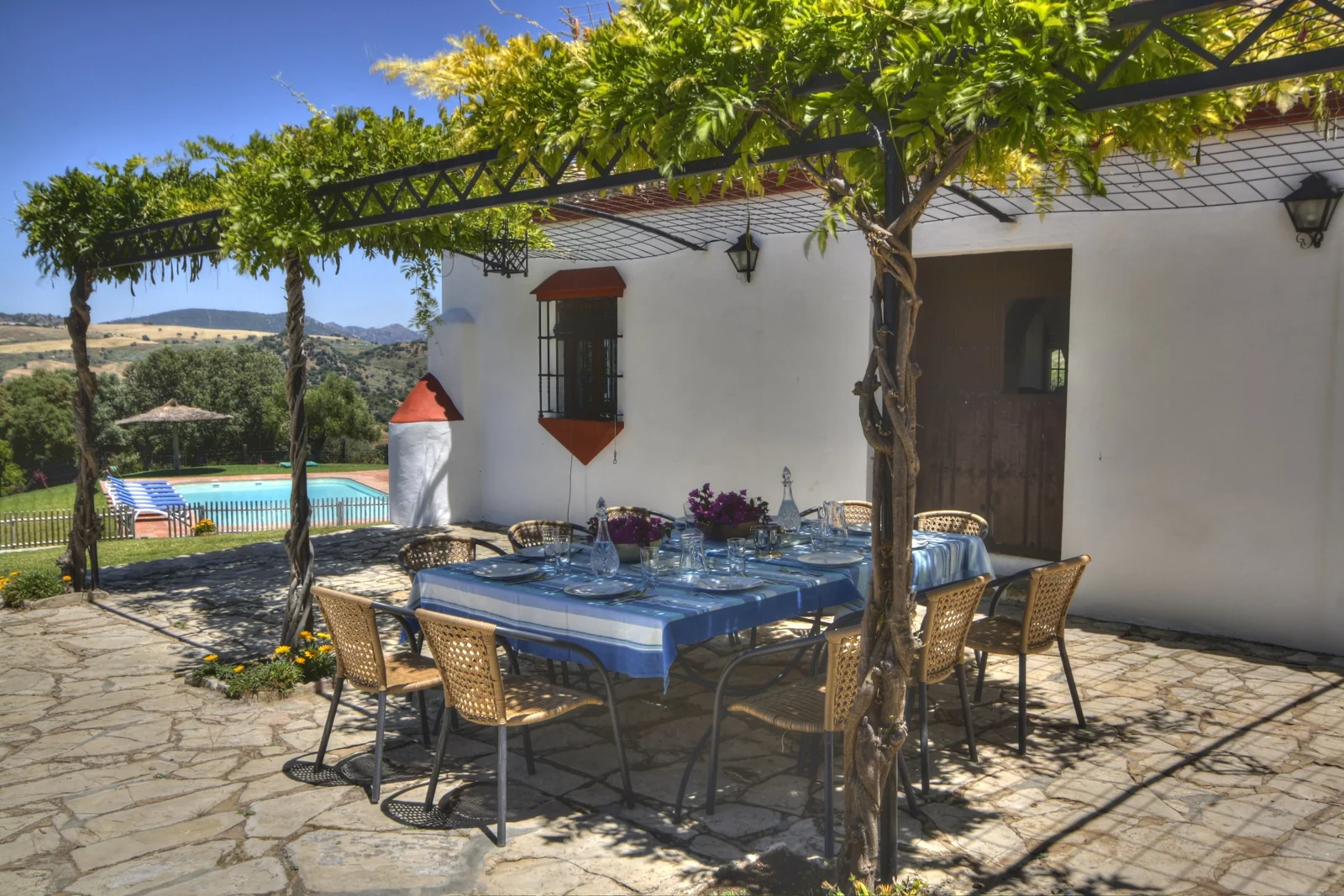 Terraza exterior del cortijo bajo una pérgola · El Puerto del Timón
