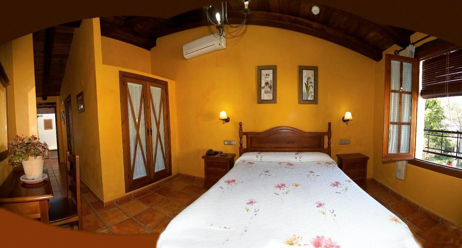 Habitación doble del hotel con techo de madera y cabecero de madera · Hotel Rural Enrique Calvillo
