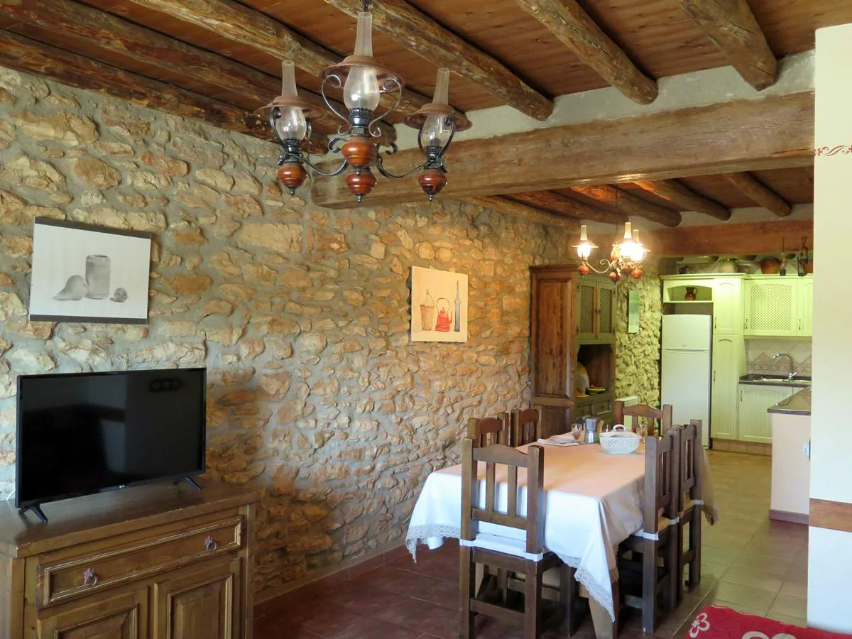 Comedor con muros de piedra y vigas de madera · Casa El Ros I y II