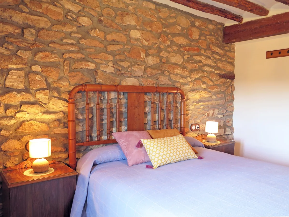 Dormitorio doble con pared de piedra · Casa El Ros I y II