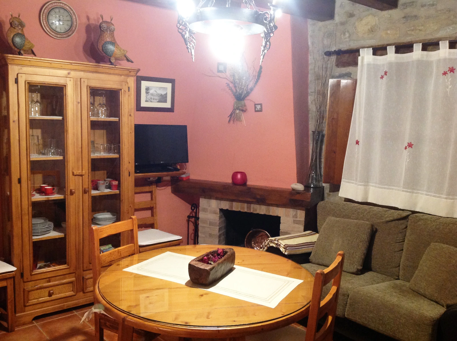 Salón comedor con chimenea y mueble de madera de la casa identificada como baix. · Casa Rural Torre Gargallo