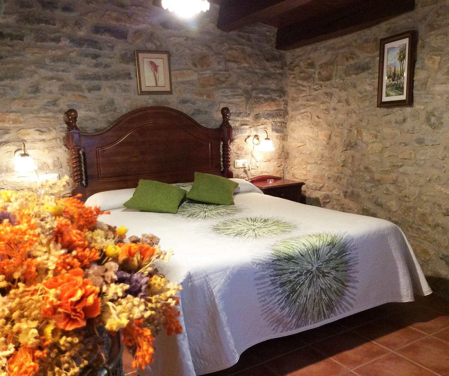Dormitorio de matrimonio con cabecero de madera y pared de piedra, casa dalt. · Casa Rural Torre Gargallo