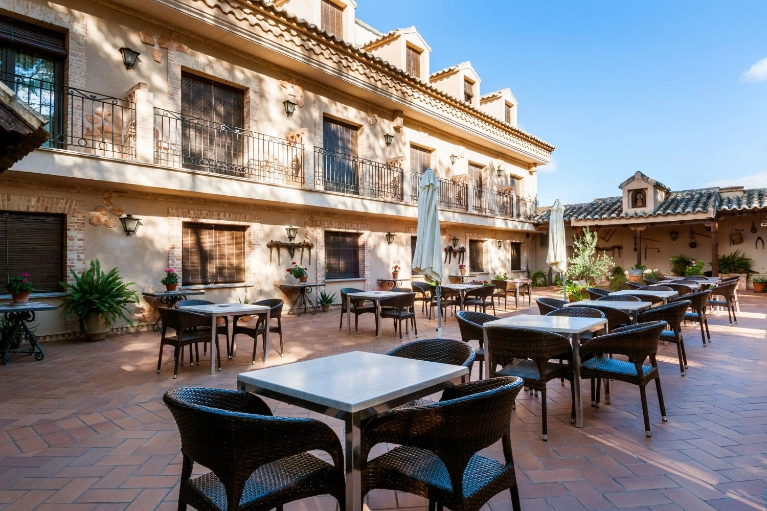 Patio exterior del Hotel Doña Manuela con mesas. · Hotel Doña Manuela
