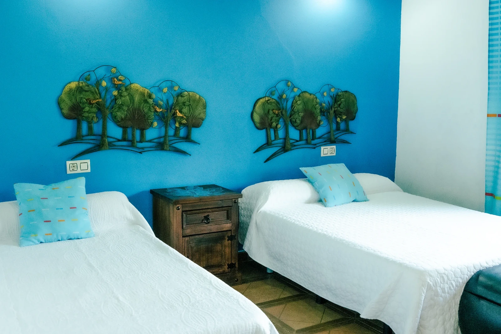 Dormitorio de dos camas y pared azul de una casa del complejo. · El Rincón de Cabañeros