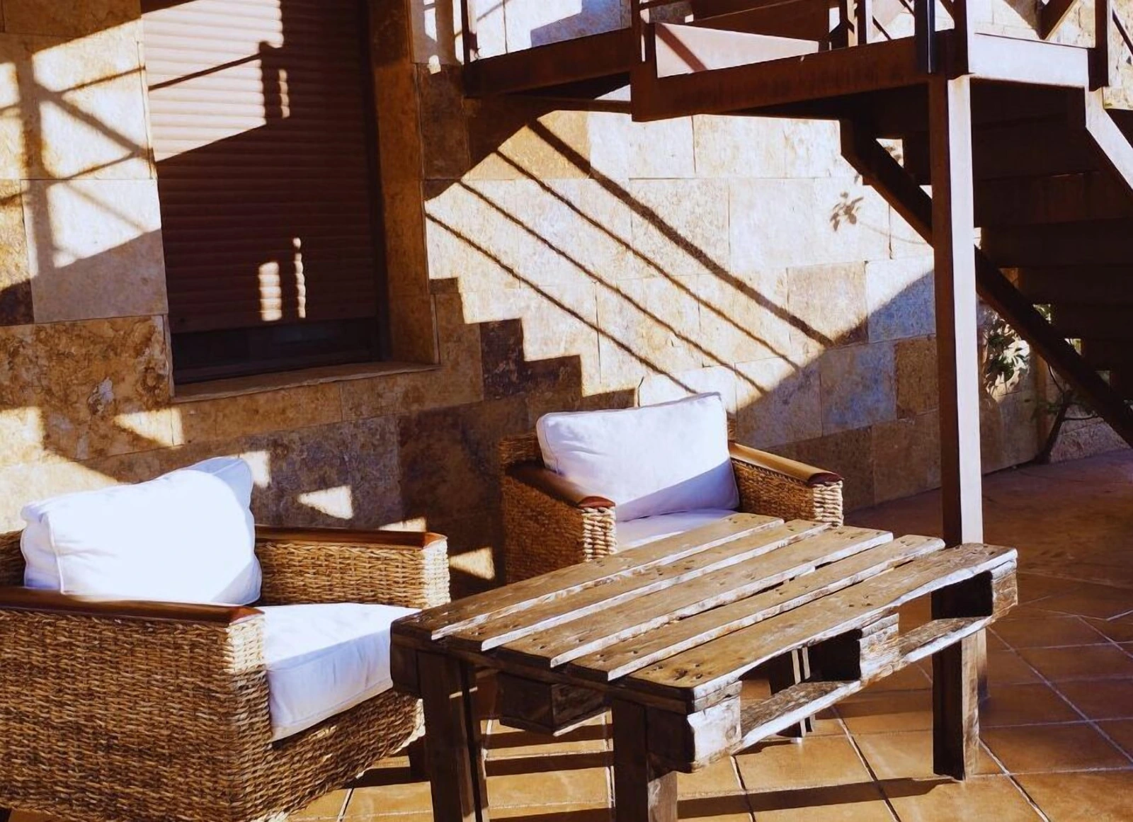 Patio interior con mesa, escalera y muros de piedra. · Casa Rural Hidalgo