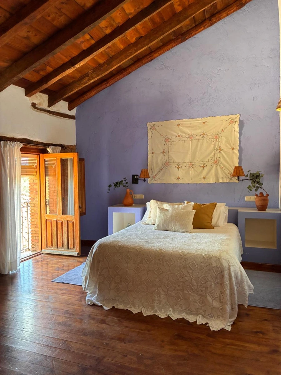Dormitorio de La Cerquilla del Médico con pared azul y techo de madera. · La Cerquilla del Médico