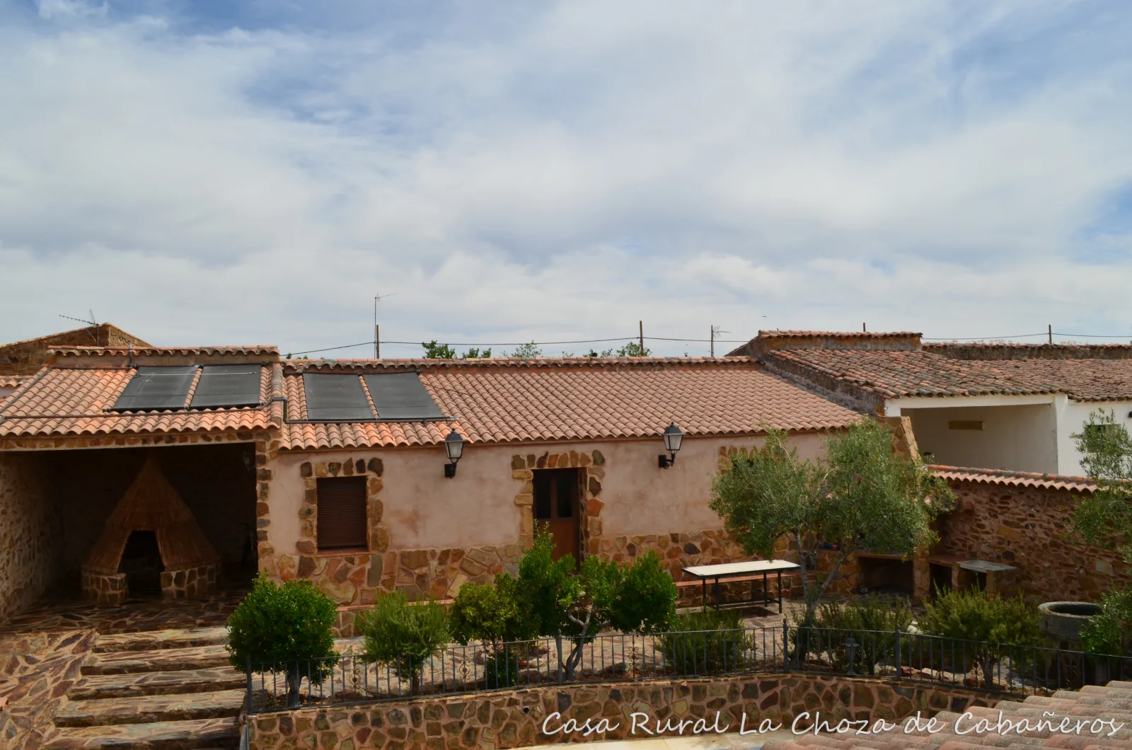 Patio interior de la casa con jardín, porche y zona de piscina · La Choza de Cabañeros