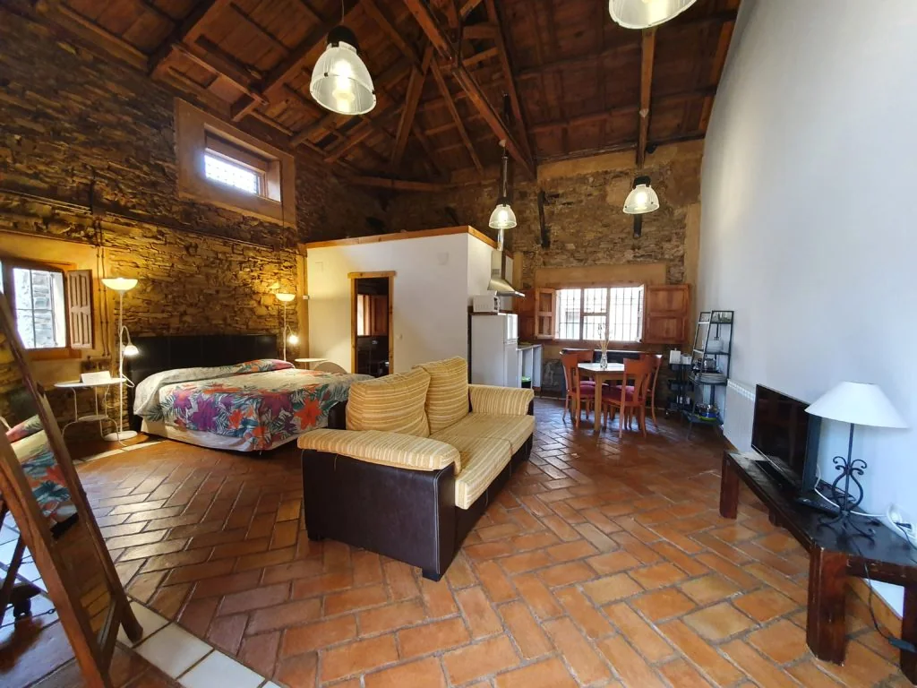 Estudio de La Posada del Corralón con cama, sofá y paredes de piedra