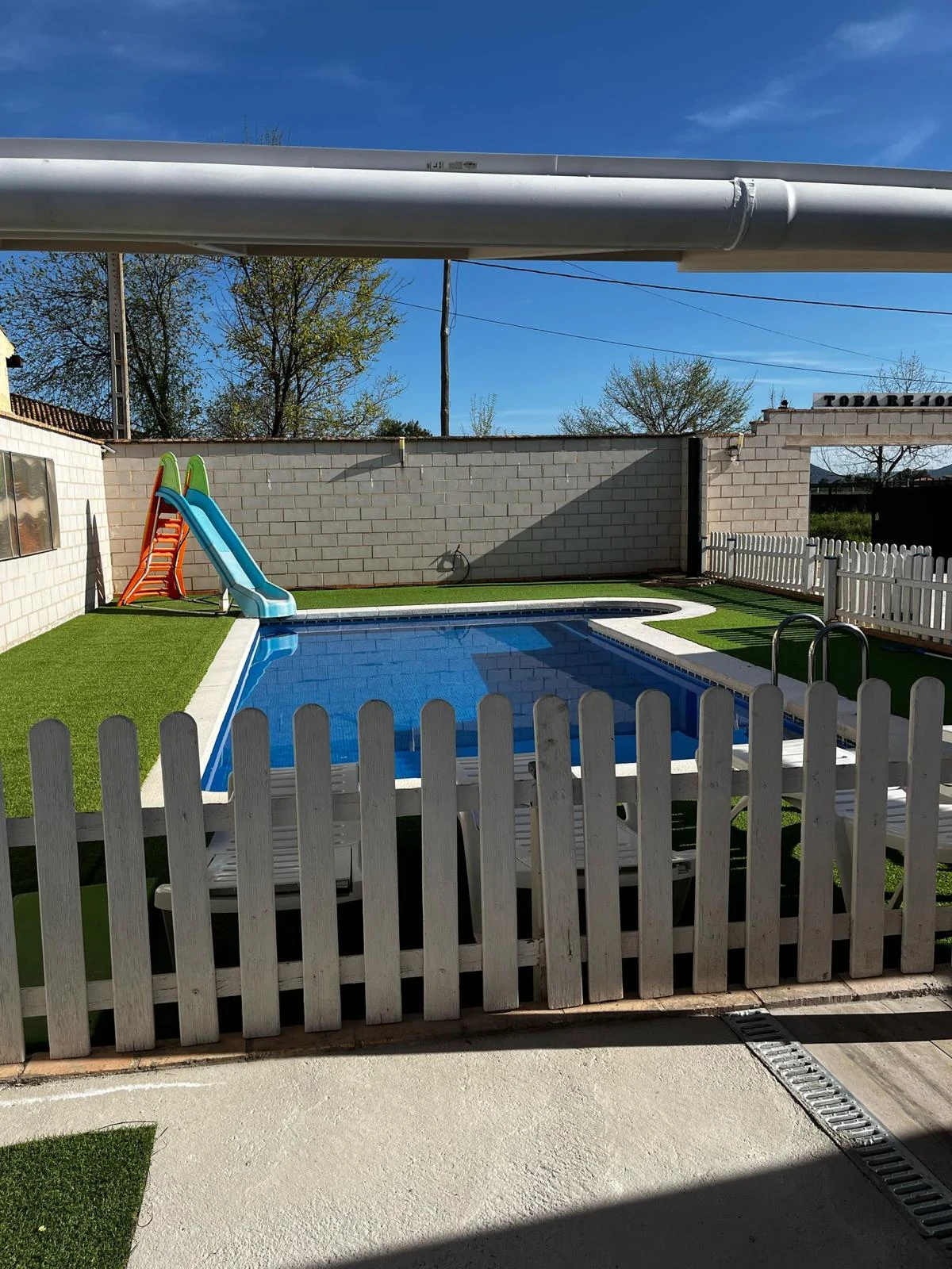 Piscina vallada con tobogán infantil en Casa Rural Tobarejos