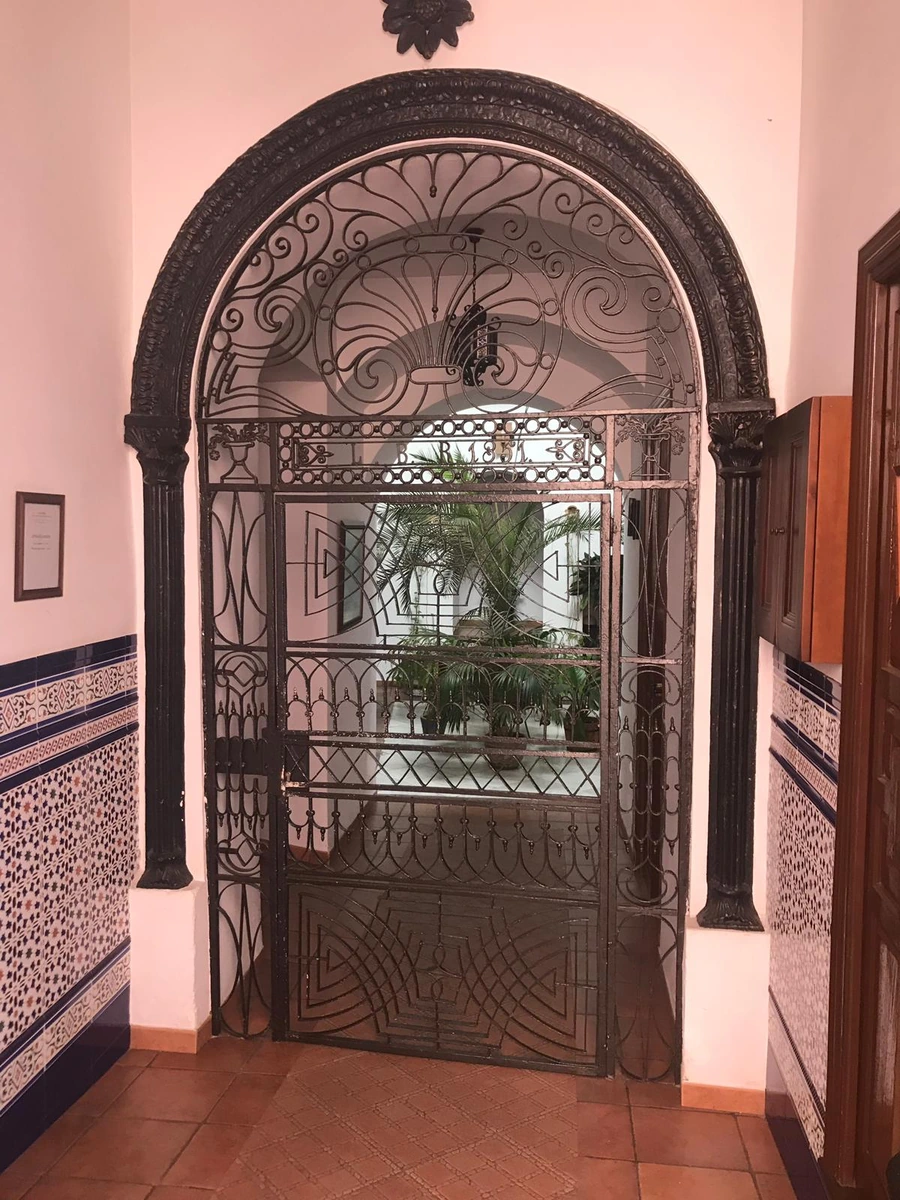 Cancela de hierro de la entrada, con el patio visible al fondo. · Casa Maika
