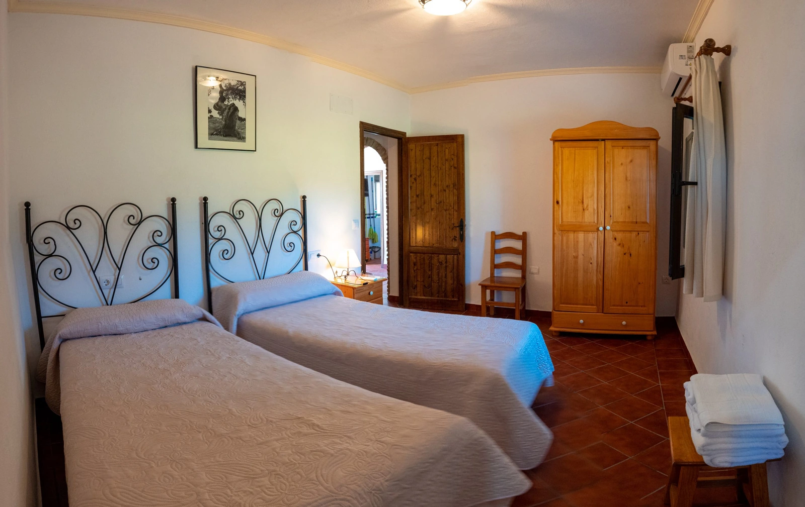 Dormitorio doble con dos camas, cabeceros de hierro y armario de madera. · Cortijo Charcollana