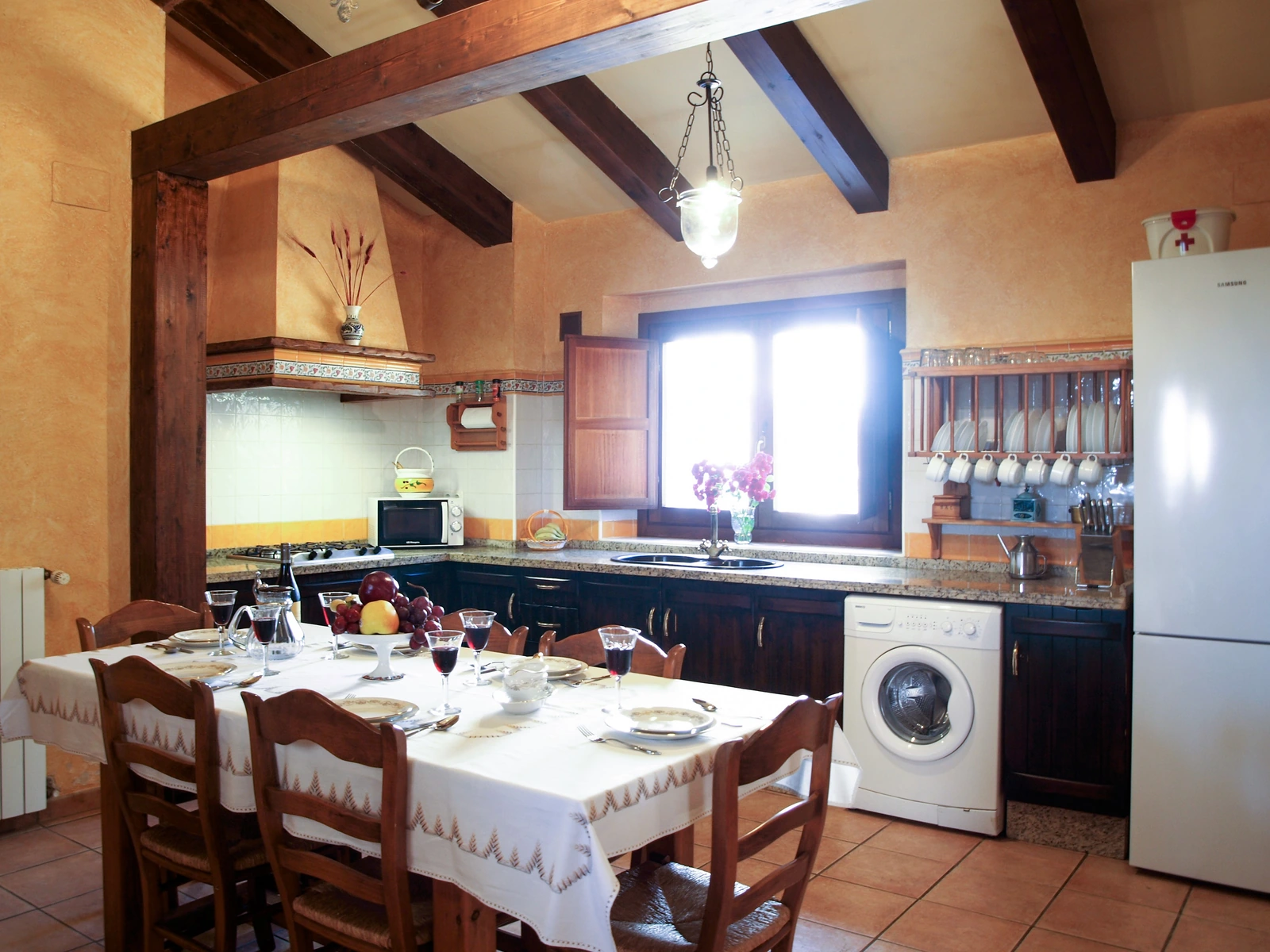 Cocina y comedor abiertos, con mesa y vigas de madera. · Cortijo de Camama