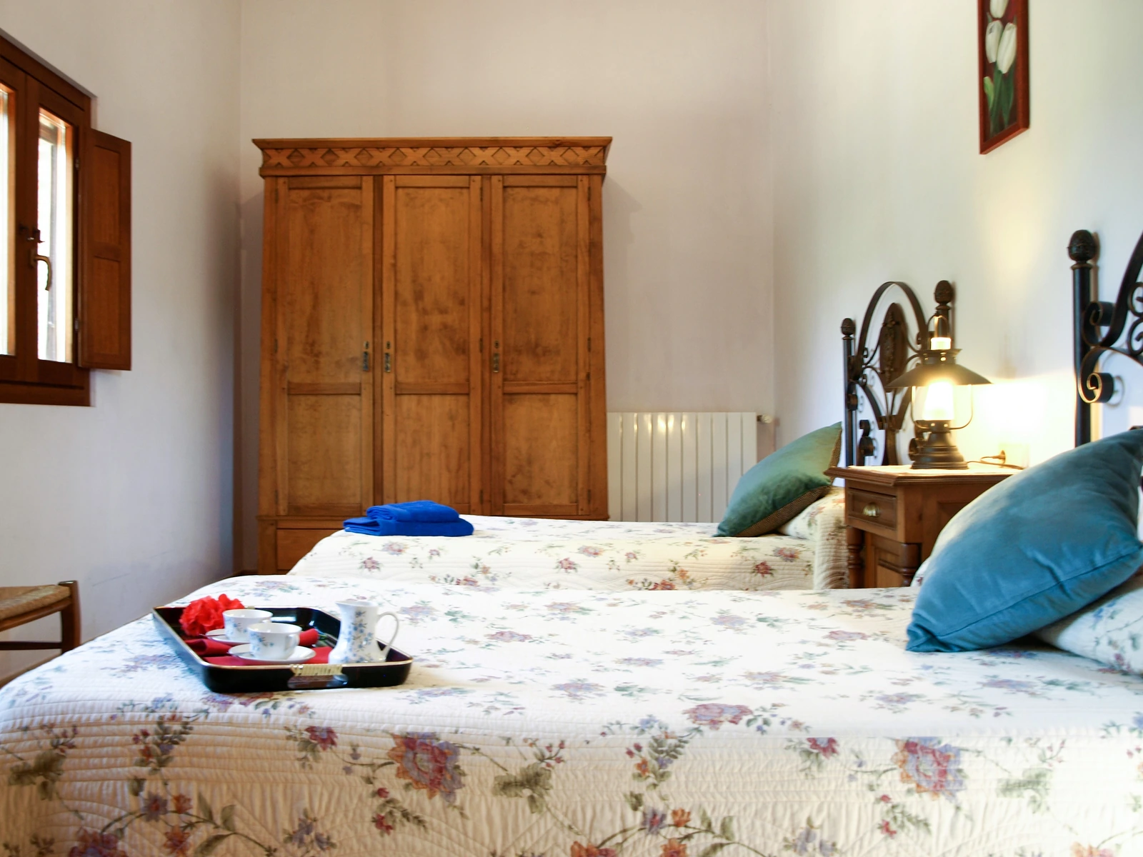 Dormitorio de matrimonio con armario de madera y ropa de cama floral. · Cortijo de Camama