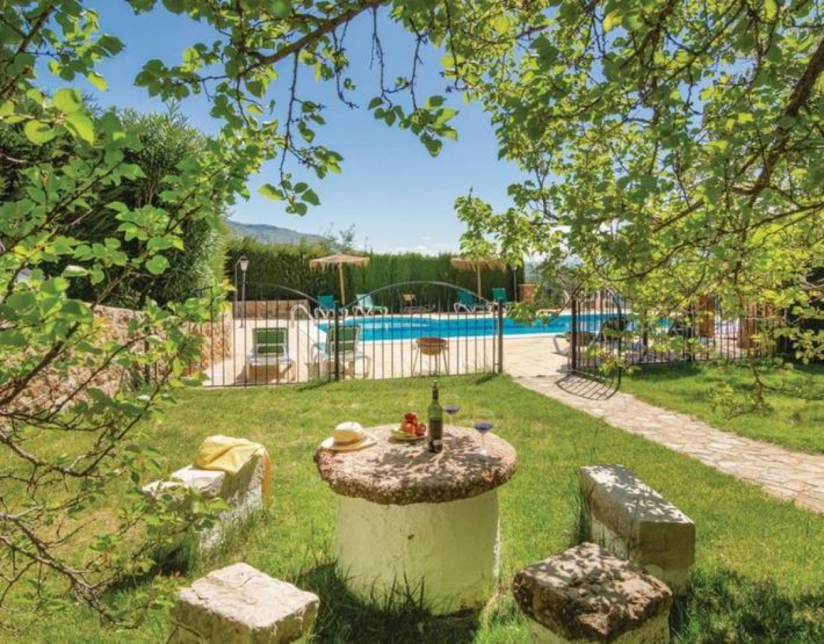 Jardín con fuente y piscina al fondo. · Cortijo La Zamora