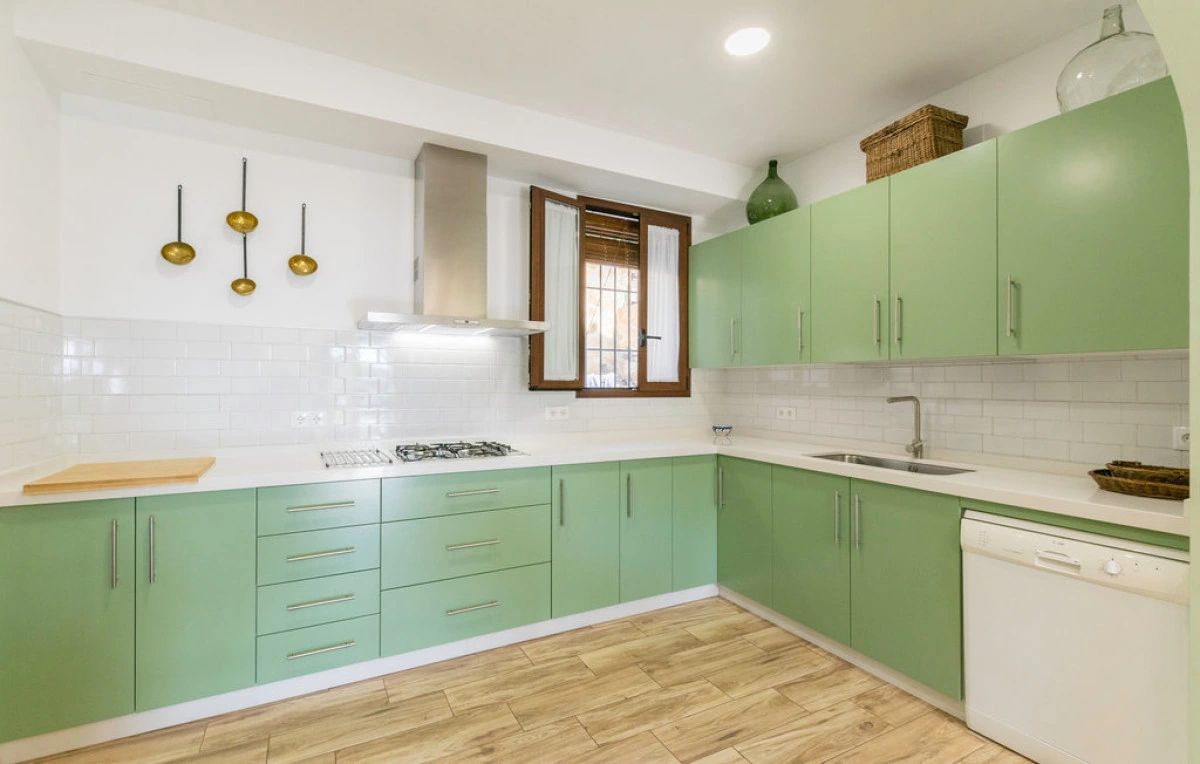 Cocina abierta con muebles verdes y encimera clara. · Cortijo La Zamora