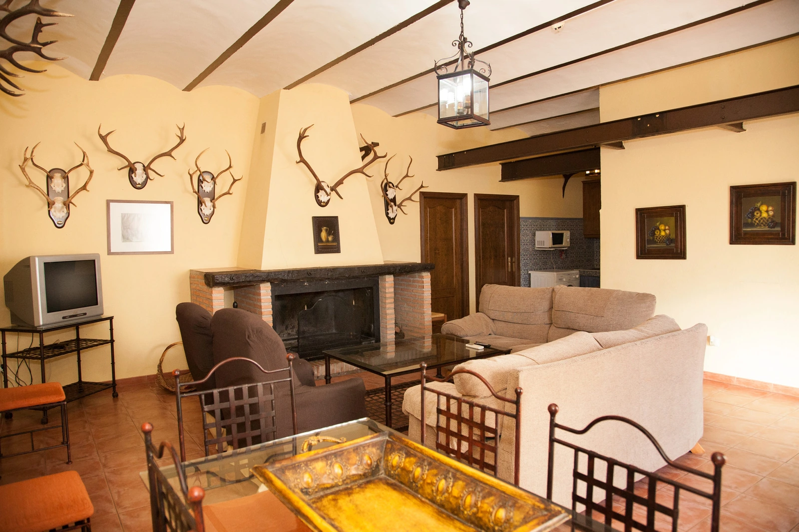 Salón de El Molino con chimenea y vigas de madera. · Cortijo Molino San Juan