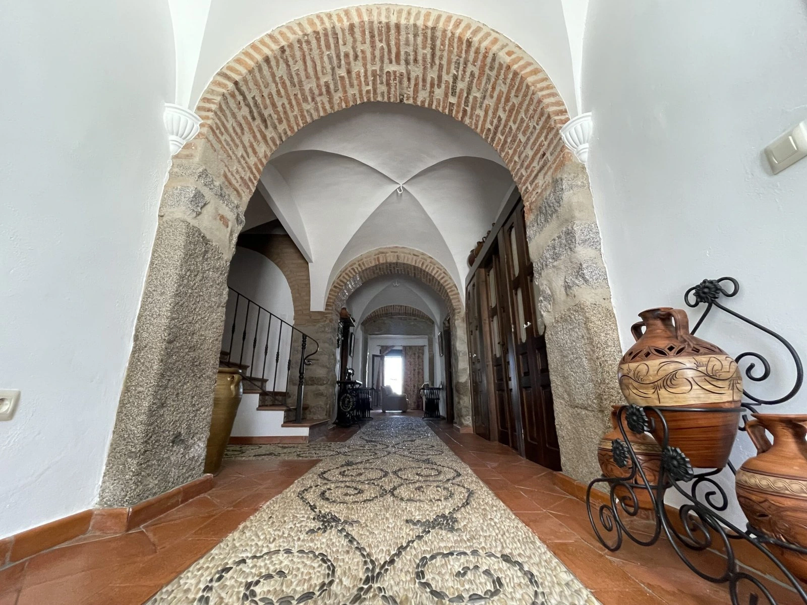 Pasillo interior con arcos de ladrillo, bóvedas blancas y suelo decorado. · Casa Rural El Verdinal