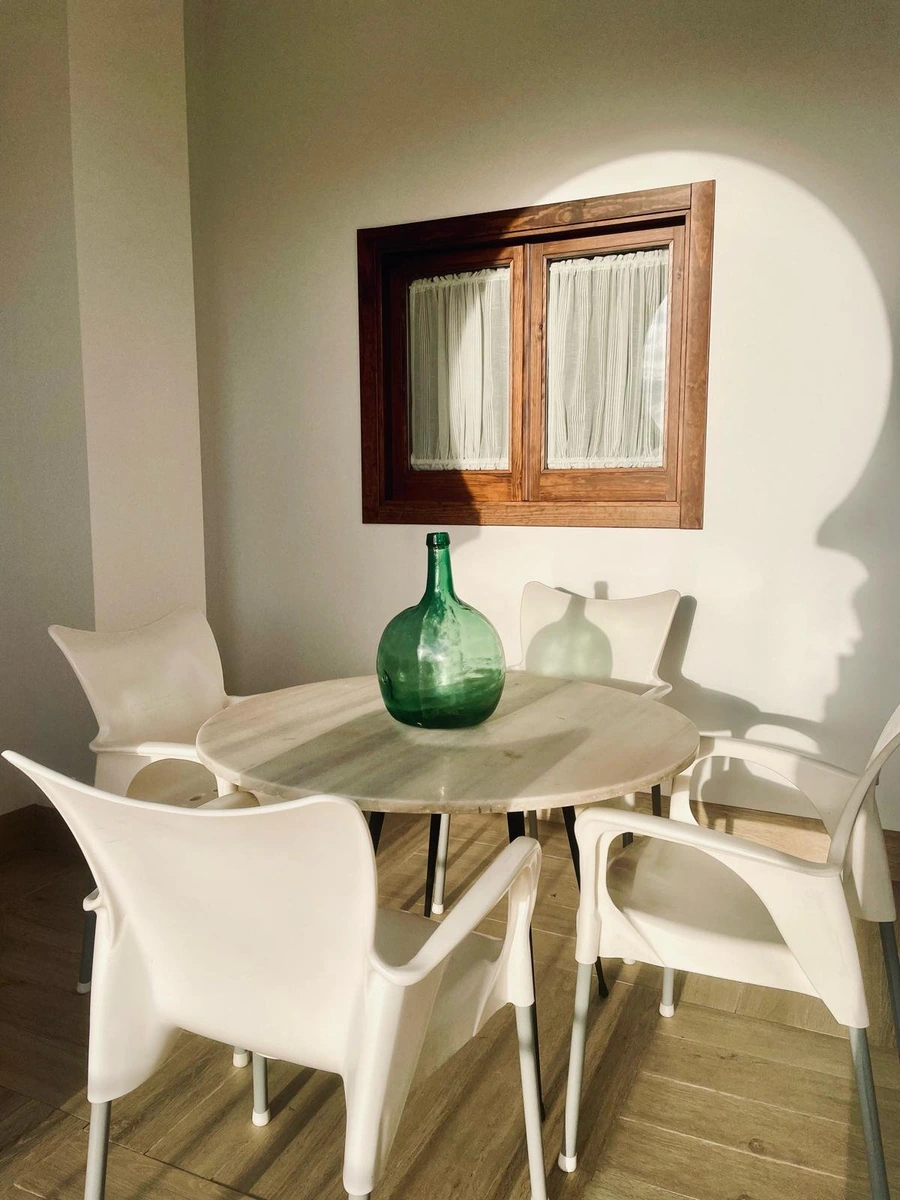 Mesa y sillas del comedor, junto a una pared blanca y espejo. · Casa Rural El Verdinal