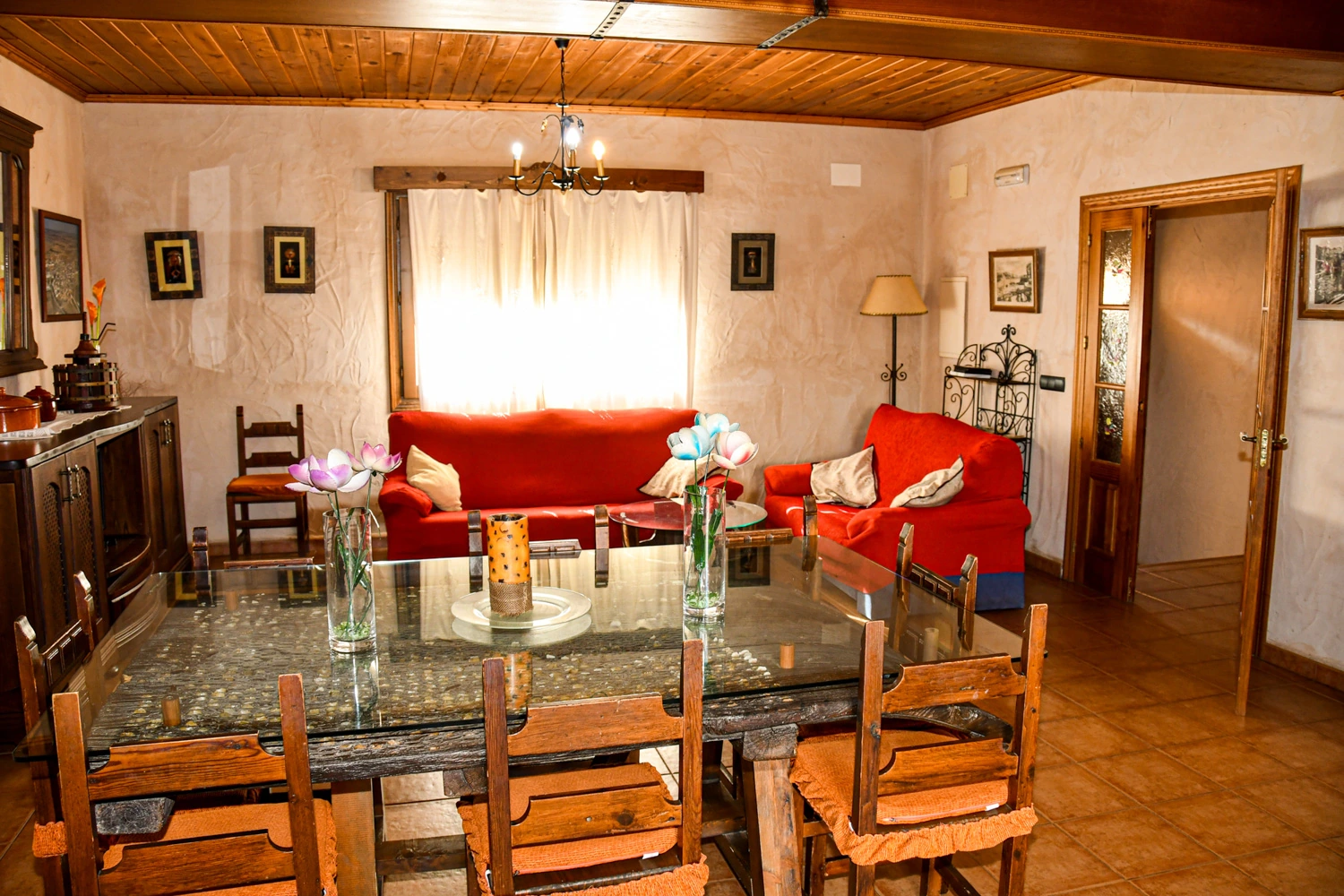 Salón comedor con sofás rojos de la Casa Rural 1. · La Cueva de Cirondo