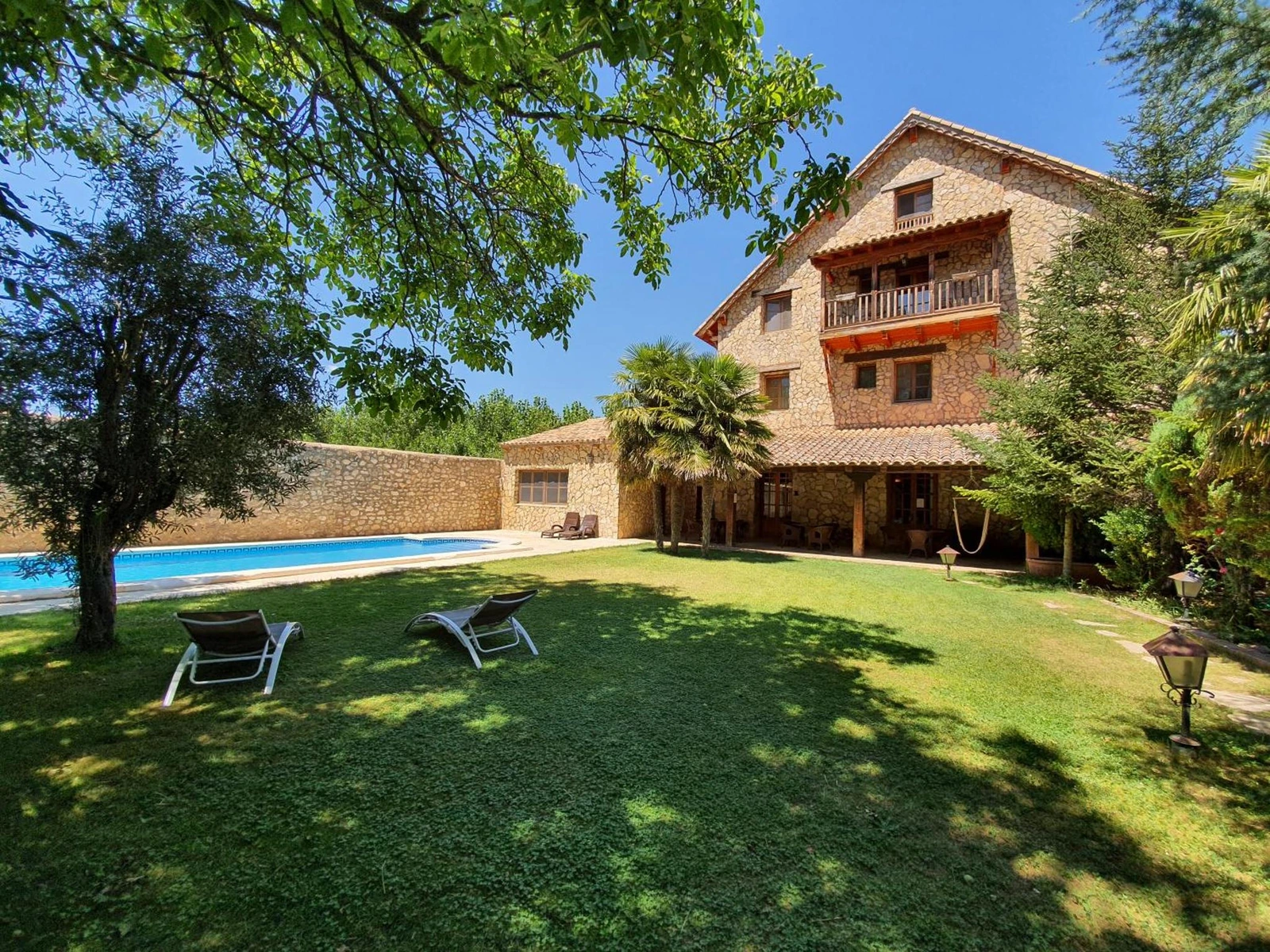 Jardín con tumbonas y vista de la casa. · Tierras de Moya