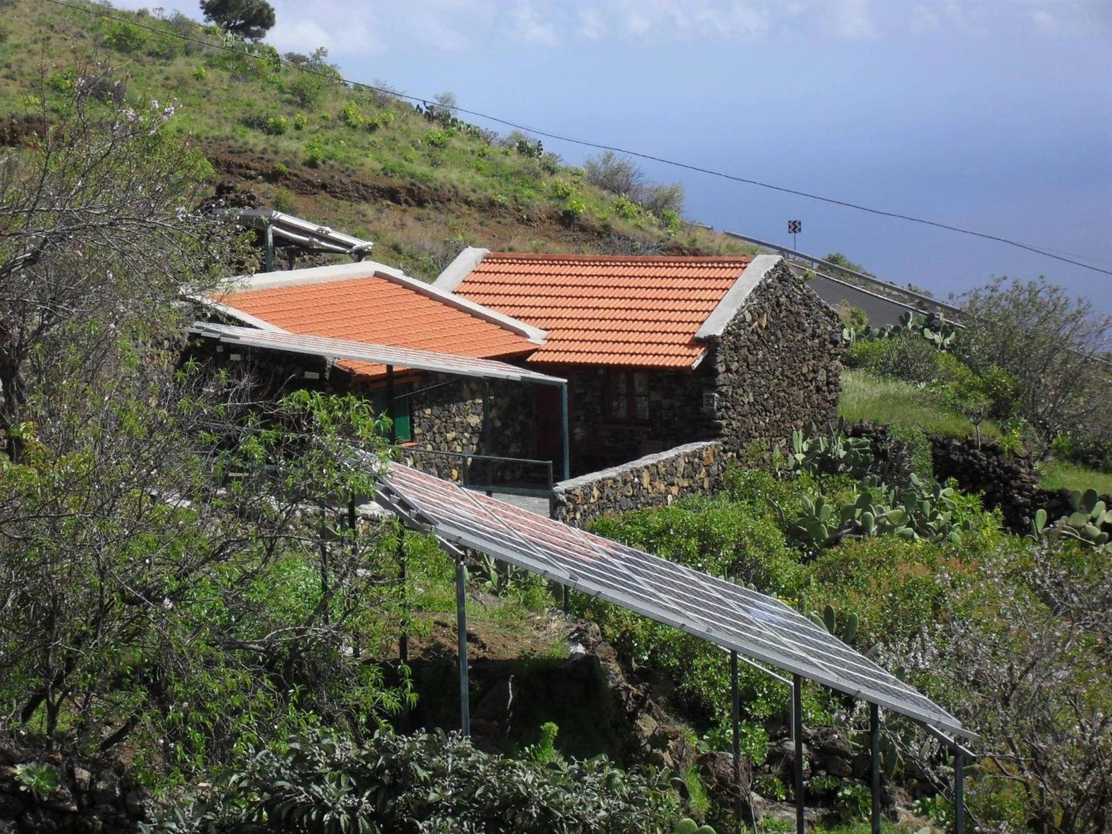 Vista de la casa entre los huertos y la ladera. · Casa Rural Abuelo Pancho
