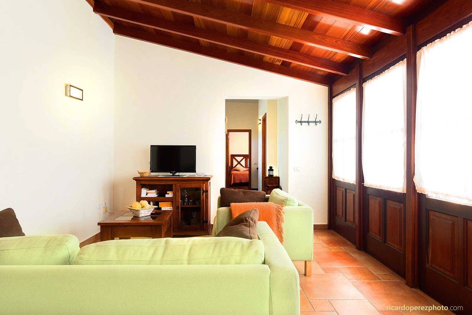Salón de Casa del Abuelito Julián, con sofás verdes y techo de madera. · Casa del Abuelito Julián