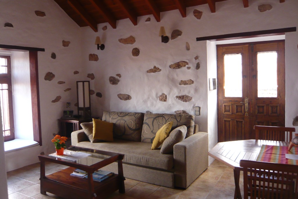 Salón de Casa de la Burra con paredes de piedra y techo de madera