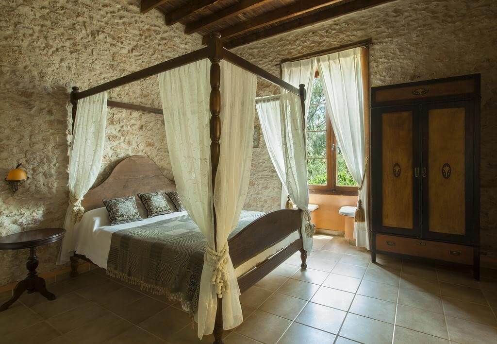 Habitación con cama con dosel y paredes de piedra · Hotel Rural Era de la Corte