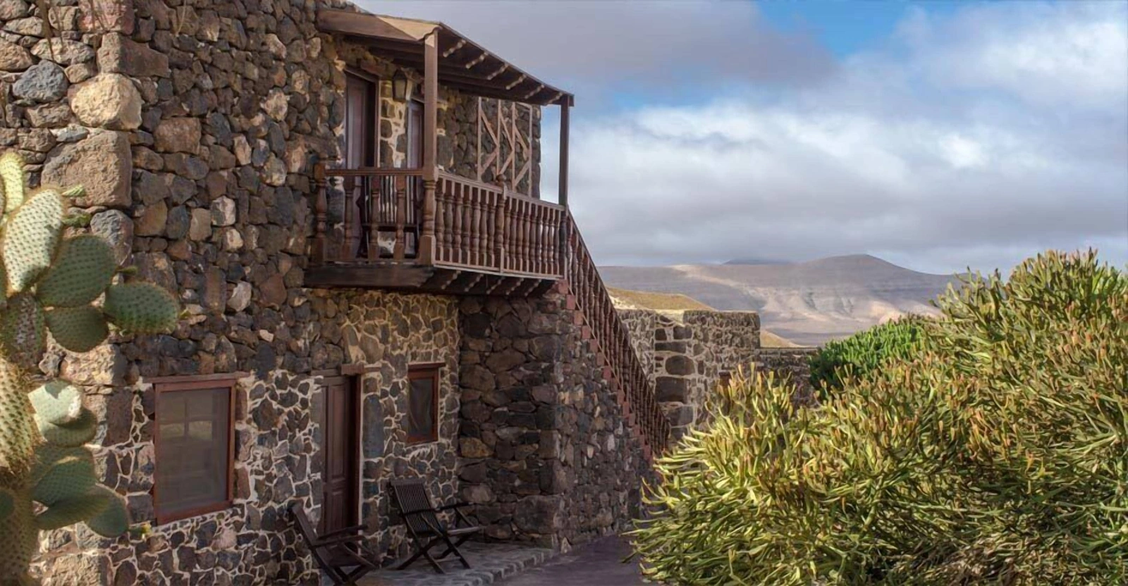 Fachada con balcón de madera y escalera exterior del hotel. · Hotel Rural Mahoh