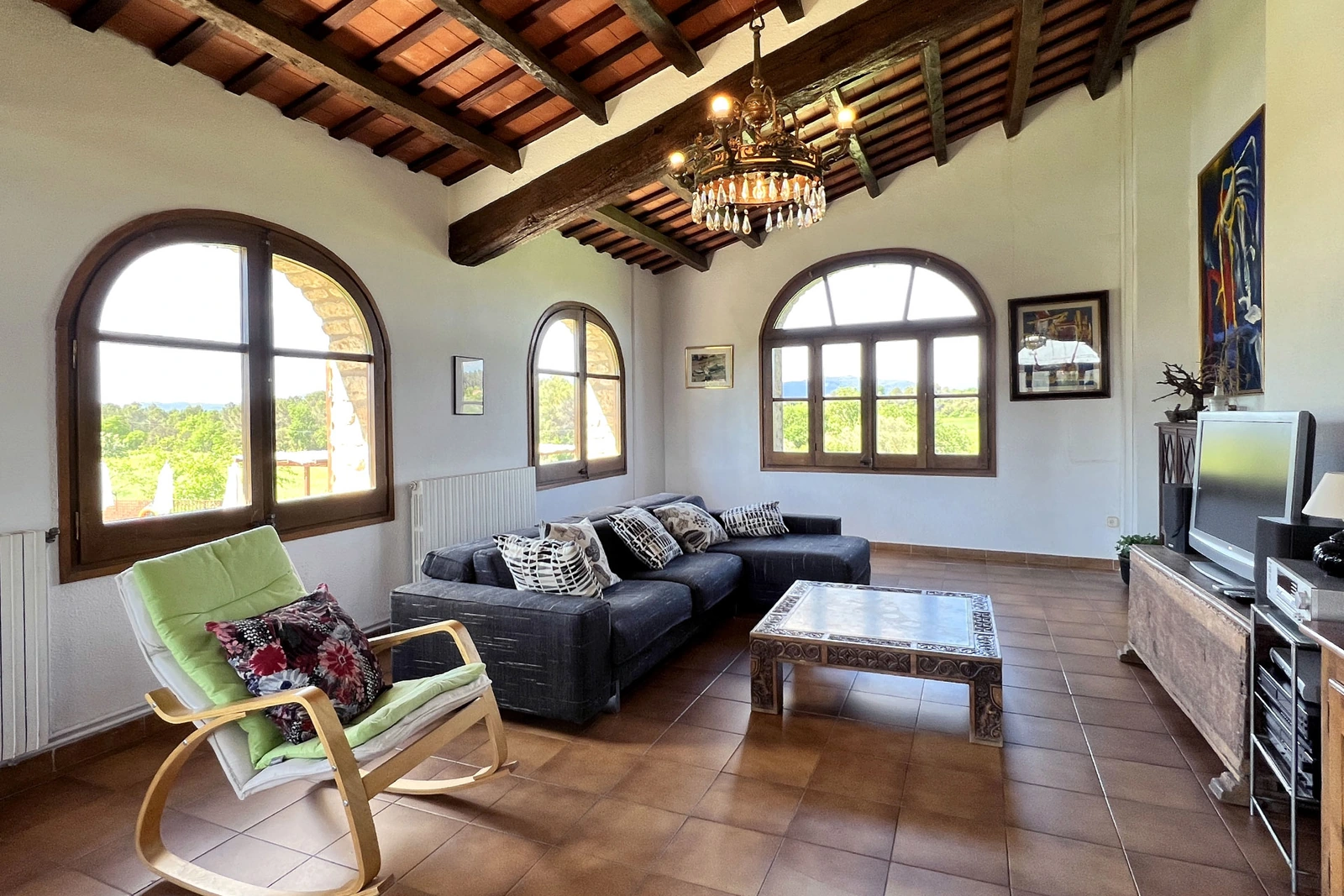 Salón con sofás, ventanas arqueadas y vigas de madera. · Can Masó