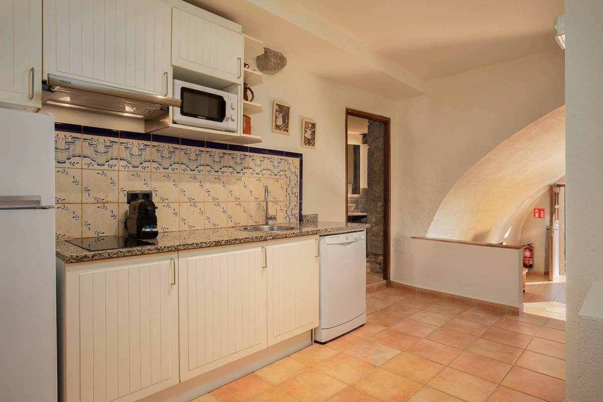 Cocina de El Galliner, con azulejos decorados y muebles claros. · El Nus de Pedra