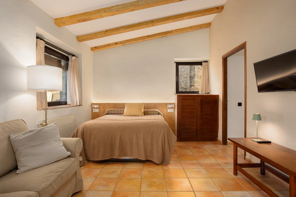 Zona de descanso y salón de El Celler en un espacio abierto, con vigas de madera. · El Nus de Pedra