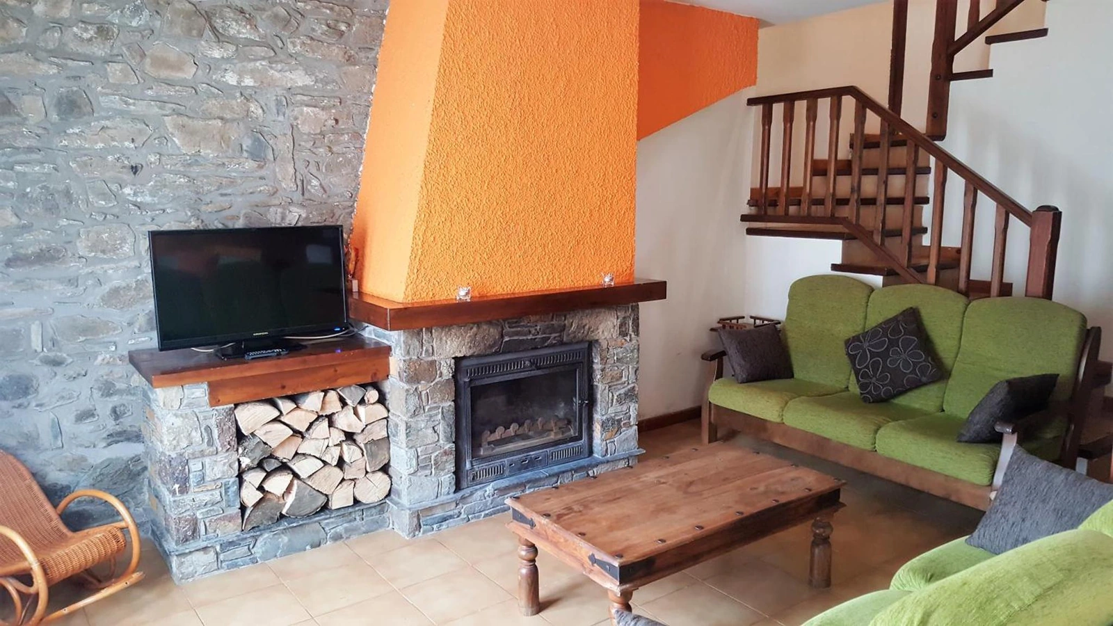 Sala con chimenea y sofá verde de una casita de dos habitaciones. · Les Barnedes