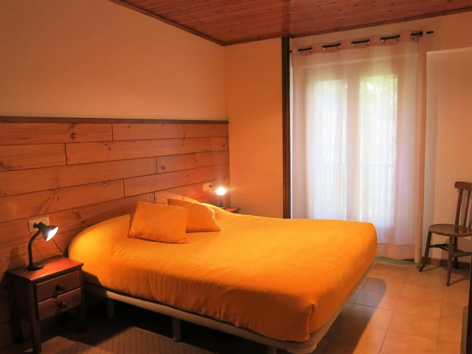 Cama doble con cabecero de madera en una casita de dos habitaciones. · Les Barnedes