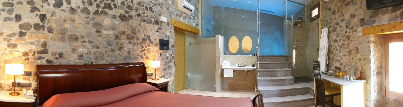 Suite nº 5, con cama y escalera hacia el espacio de baño y piscina privada en el nivel superior. · Mas La Casassa