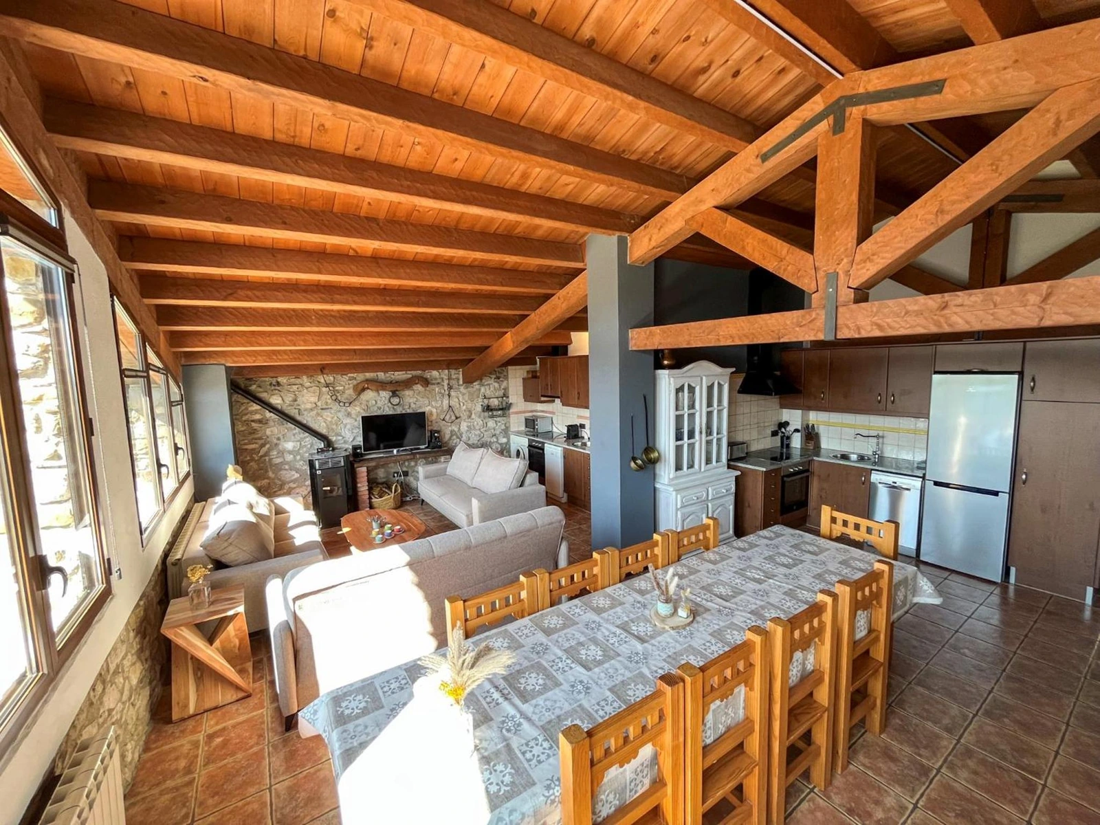 Comedor bajo vigas de madera, con la zona de estar al fondo. · Mas Merolla