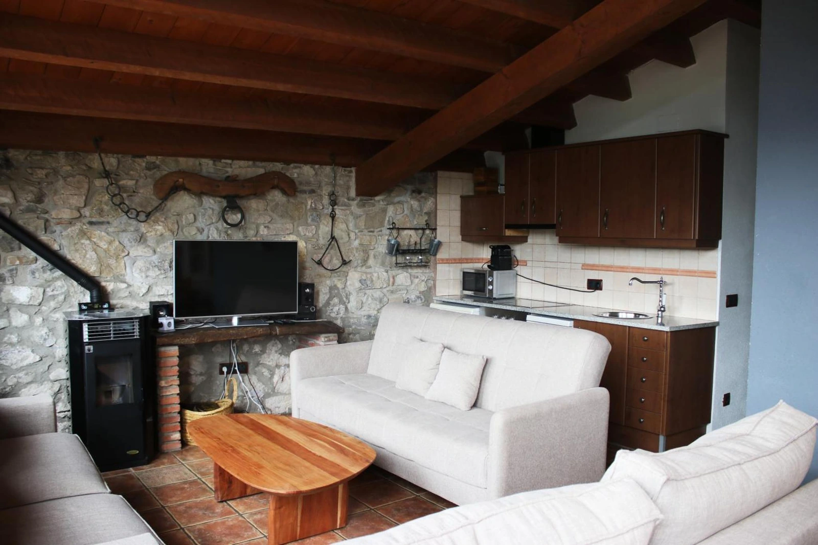 Sala de estar con sofá blanco, mesa de madera y pared de piedra. · Mas Merolla