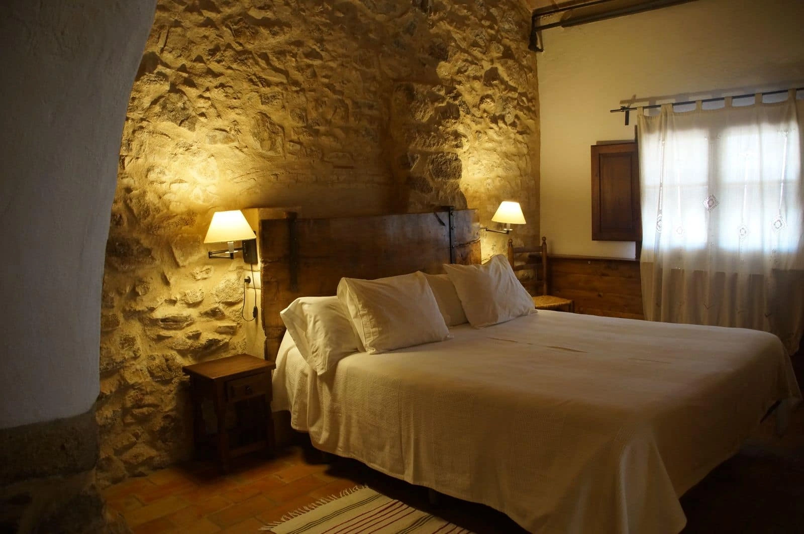 Dormitorio de El Celler, con paredes de piedra. · Mas Roquet