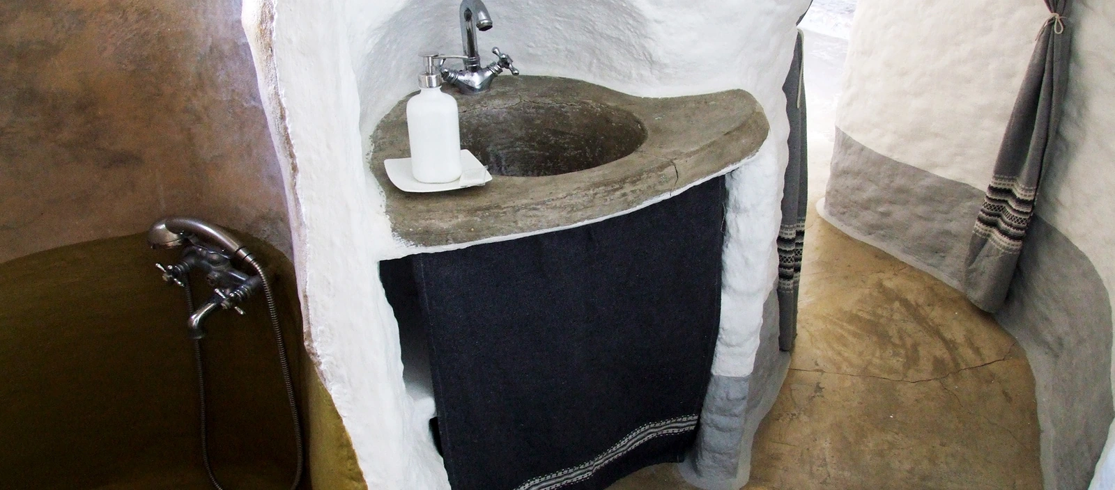 Baño de la cueva 1 con lavabo de piedra y ducha. · Al Jatib
