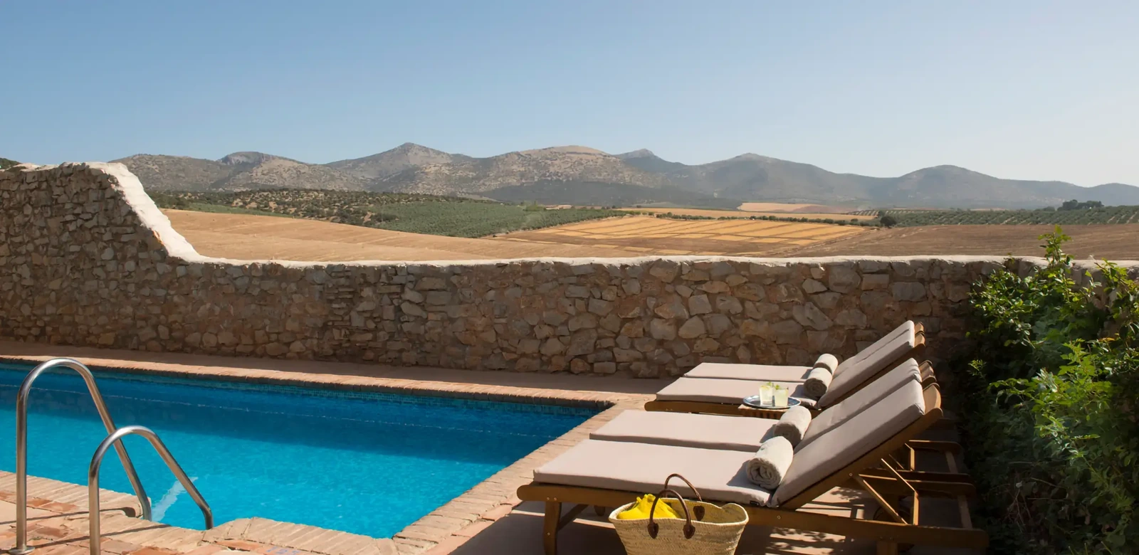 Piscina común del hotel, con tumbonas y vistas a la campiña. · Hotel Cortijo del Marqués