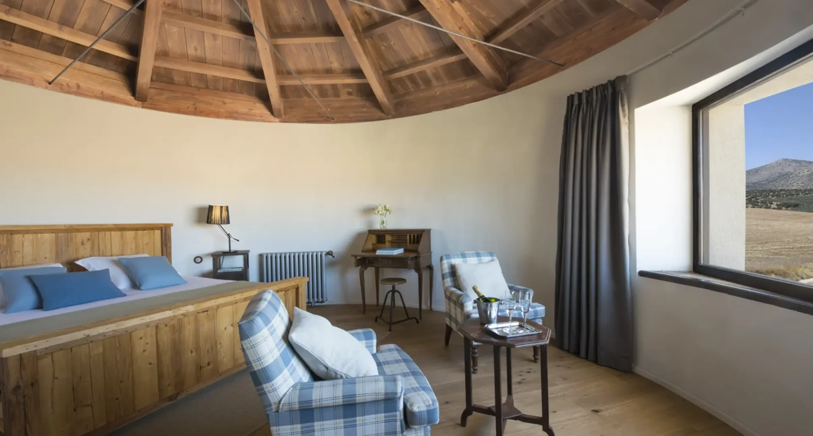 Suite El Silo: dormitorio circular con zona de estar y ventanal. · Hotel Cortijo del Marqués