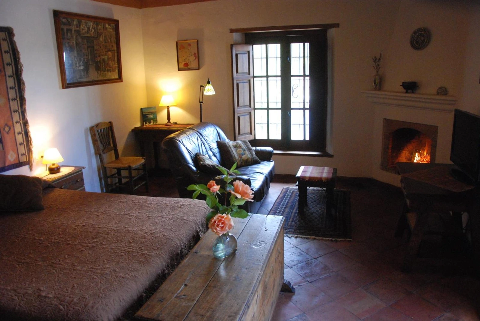 El Ático: zona de estar con sofá y chimenea junto a la cama. · Cortijo Prado Toro