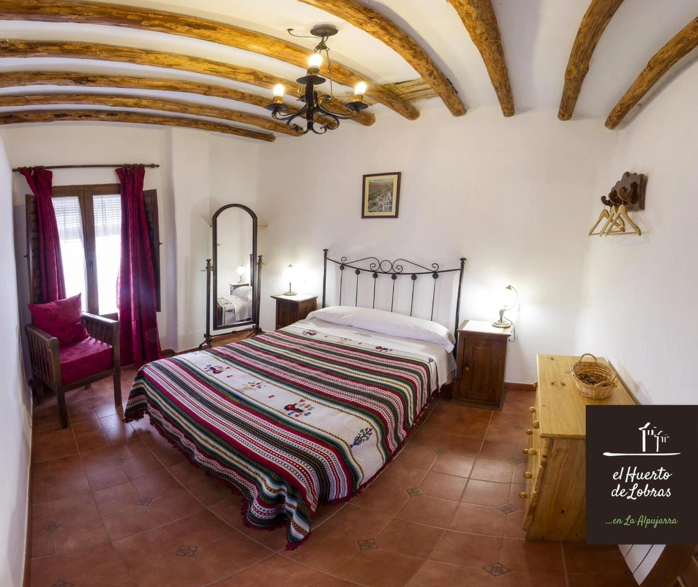 Los Cerezos: dormitorio con cama de matrimonio y vigas curvas. · El Huerto de Lobras