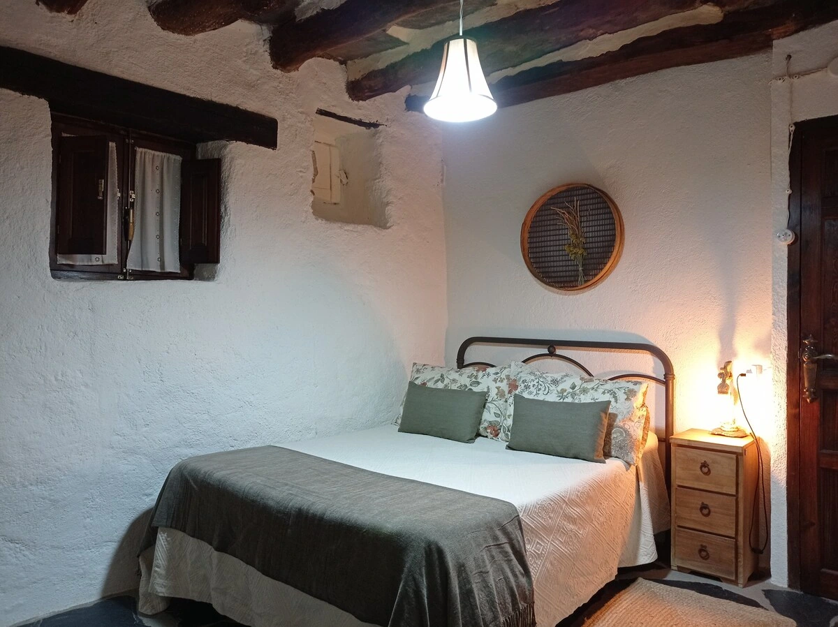 Dormitorio con cabecero de hierro y vigas originales · La Abuela Mercedes